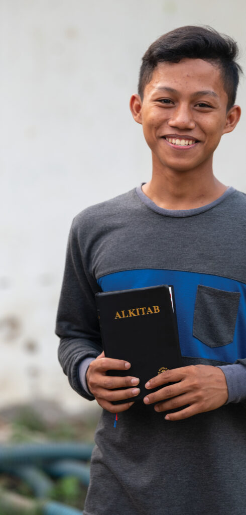 man smiles while holding a bible 