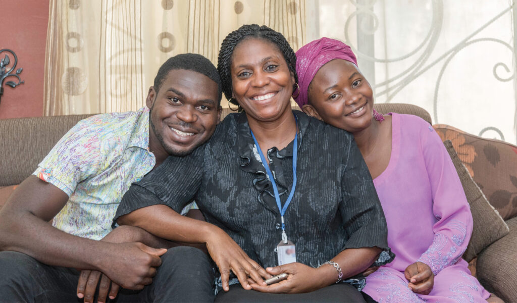 Mother sits smiling with her son and daughter