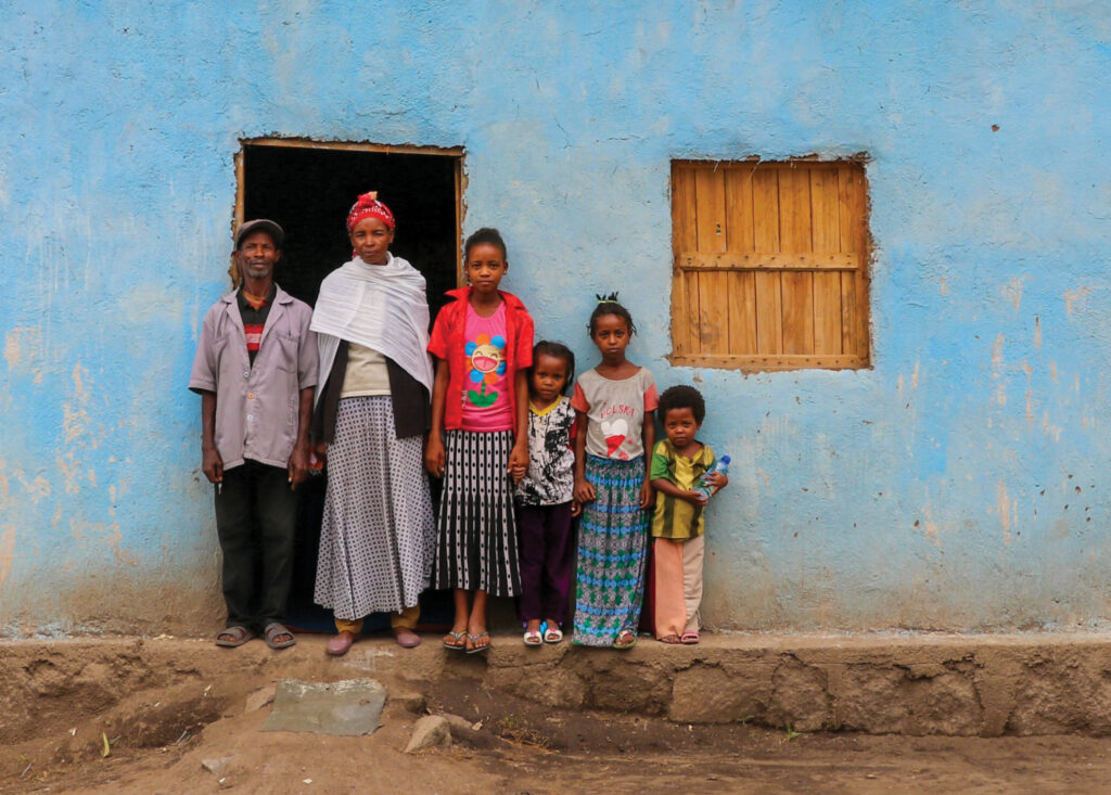 a family stands for their photograph outside a building, most likely their home