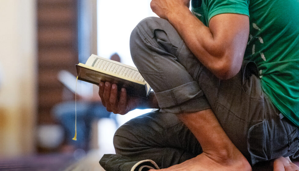 man kneels while he reads the Bible