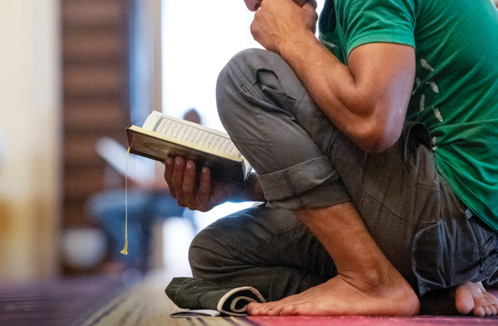 man kneels while he reads the Bible